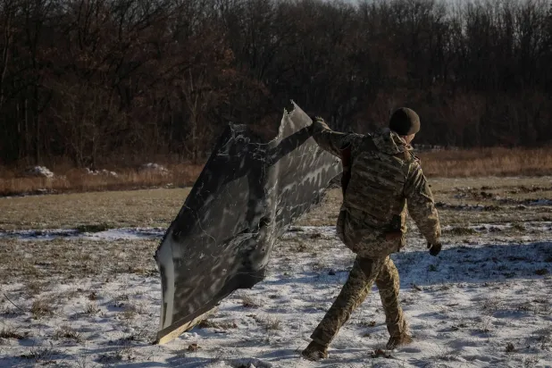 جندي أوكراني يحمل جزءاً من طائرة بدون طيار روسية أُسقطت بالقرب من كييف (رويترز)