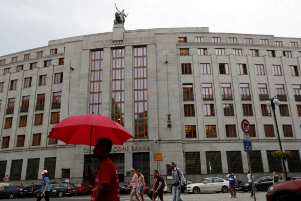رجل يحمل مظلة أمام المصرف المركزي التشيكي في براغ (رويترز)
