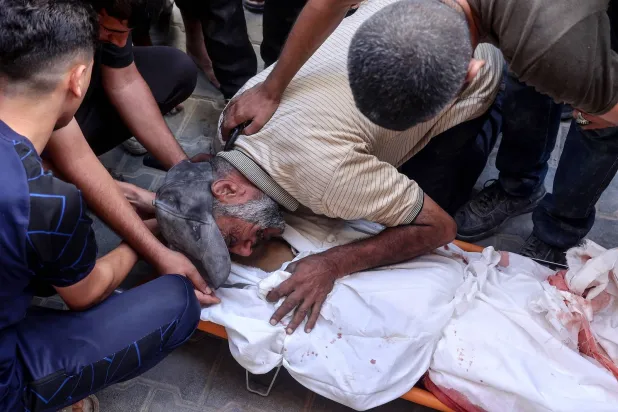 فلسطينيون يبكون على جثة أحد ضحايا القصف الإسرائيلي في النصيرات وسط قطاع غزة (أ.ف.ب)