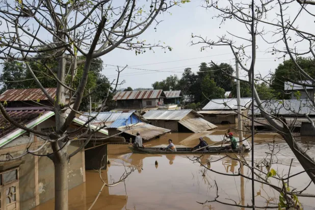  Myanmar'da insanlar sular altında kalan bir yolu geçmek için tekne kullanıyor (AP)