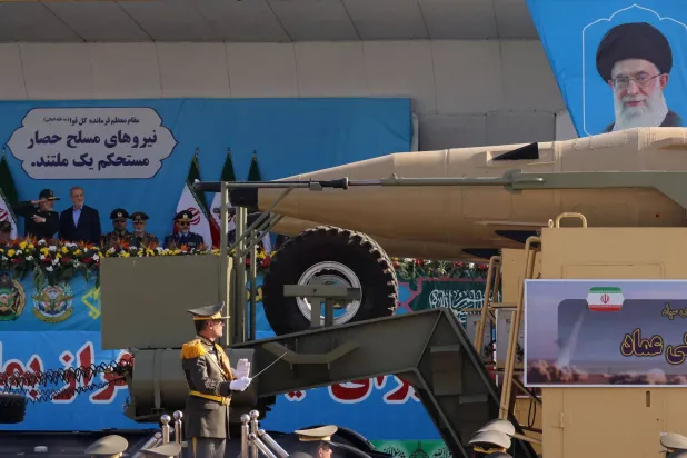 قائد الوحدة الصاروخية أمير علي حاجي زاده يتحدث إلى بزشكيان خلال مرور شاحنة تحمل صاروخ «عماد» الباليستي خلال عرض عسكري في طهران (أ.ف.ب)