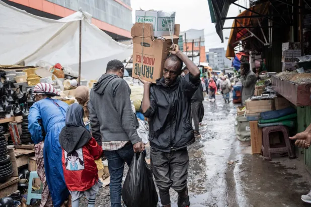 رجل ينقل كرتونة طعام في منطقة ميركاتو التاريخية بأديس أبابا (أ.ف.ب)