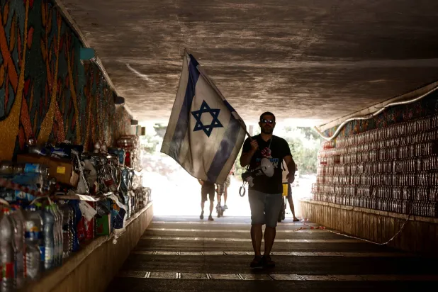 متظاهر يحمل علماً في نفق بالقرب من مظاهرة ضد الإصلاح القضائي للحكومة الإسرائيلية (أرشيفية - رويترز)