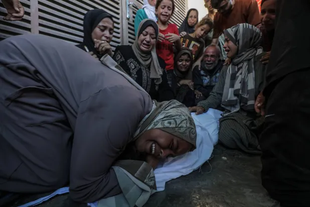 أفراد عائلة الشاب محمد صلوحة يشيعون جثمانه خلال جنازته في بلدة دير البلح وسط قطاع غزة وسط الحرب الإسرائيلية على غزة (إ.ب.أ)