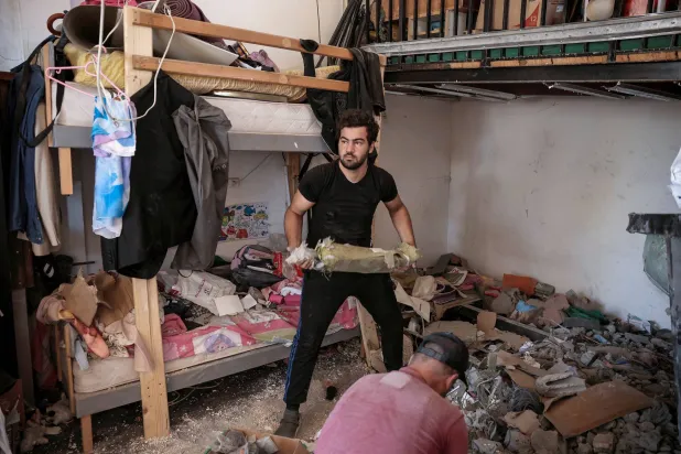 لبنانيون يرفعون الحطام من منزل شمال بيروت الخميس بعد غارة إسرائيلية (رويترز)