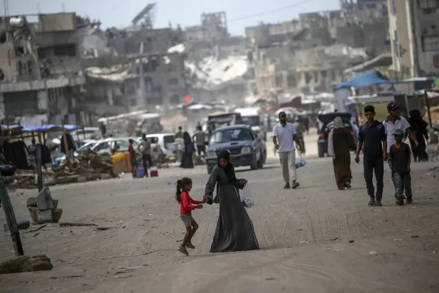 فلسطينيون نازحون داخلياً يسيرون في أحد شوارع خان يونس جنوب قطاع غزة (إ.ب.أ)