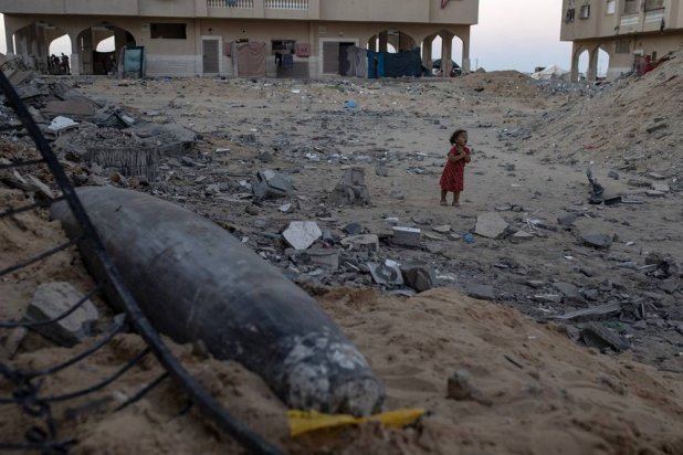 A Palestinian child plays near an unexploded Israeli missile among the rubble of a destroyed building at Khan Younis refugee camp, southern Gaza Strip, 28 September 2024. (EPA)
