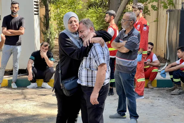 أقارب ينتظرون العثور على جثث تحت أنقاض المباني التي دمرتها غارة جوية إسرائيلية في حي عين الدلب شرق مدينة صيدا الساحلية (إ.ب.أ)