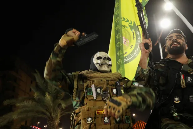 عناصر من فصيل عراقي خلال احتفال في بغداد بالرد الإيراني على إسرائيل (رويترز)