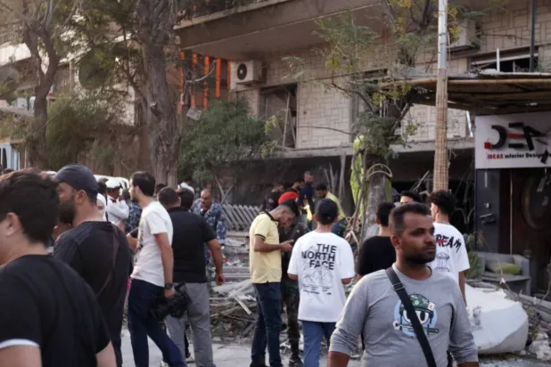 أشخاص قرب المبنى المستهدف في حي المزة بدمشق (إ.ب.أ)