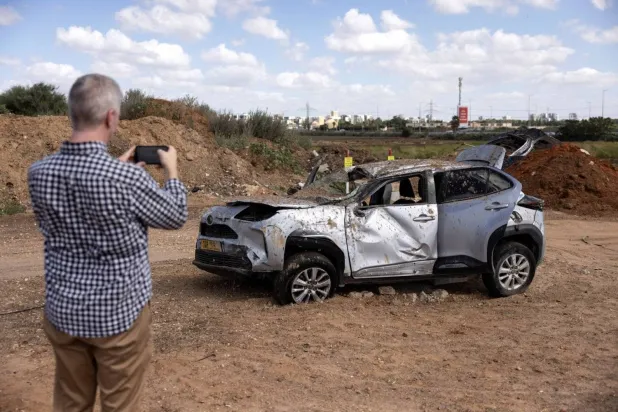 A man takes a picture of a car that was damaged in the area where a projectile landed after Iran fired a salvo of ballistic missiles at Israel, in Tel Aviv, Israel, October 2, 2024. REUTERS/Nir Elias