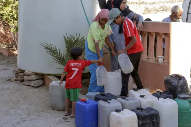 أطفال من قرية سيدي بوشتة يتزودون بالمياه الصالحة للشرب بعد تحليتها (أ.ف.ب)