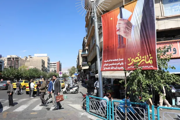 لوحة دعائية في شارع وسط طهران مكتوب عليها بالفارسية «صلاة النصر» وتظهر يد المرشد علي خامنئي ماسكاً بندقية الخميس (إ.ب.أ)