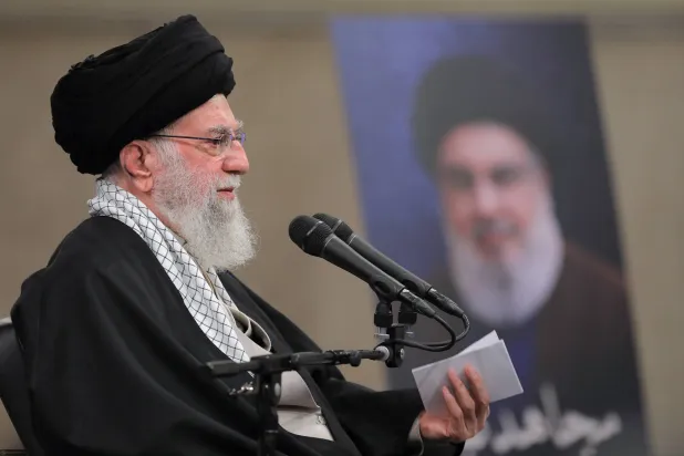خامنئي يلقي خطاباً أمام مجموعة من أنصاره وفي الخلفية صورة نصر الله (موقع المرشد)
