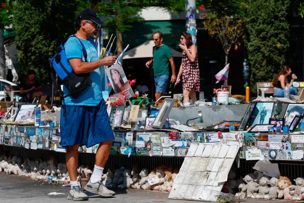 أشخاص في تل أبيب ينظرون إلى صور الرهائن المختطفين بغزة منذ 7 أكتوبر 2023 (رويترز)