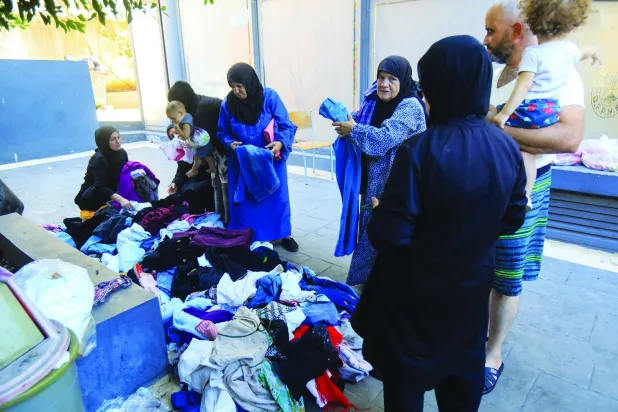 توزيع الملابس على النازحين في أحد مراكز الإيواء (أ.ف.ب)