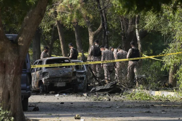 عناصر من قوات الأمن الباكستانية بجوار سيارة محطمة في موقع الانفجار قرب مطار كراتشي (أ.ب)