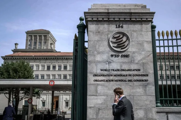 رجل يتحدث في الهاتف لدى مروره أمام مقر منظمة التجارة العالمية في جنيف (أ.ف.ب)