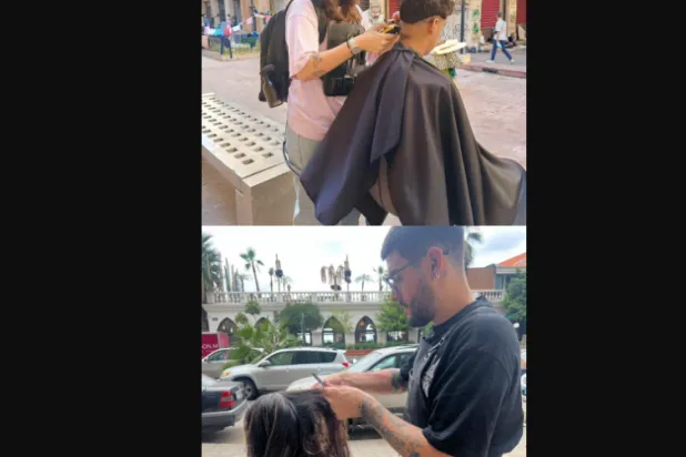 الشابة كريستي رحّال وزميلها «أبولو» يقدمان خدمة تصفيف الشعر المجانية للبنانيين النازحين بسبب الحرب في بيروت (الشرق الأوسط)