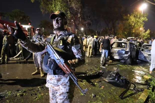 جندي يشير إلى وسائل الإعلام بينما يقوم مسؤولون أمنيون بفحص موقع انفجار تسبب في إصابة وتدمير مركبات خارج مطار كراتشي باكستان الاثنين 7 أكتوبر 2024 (أ.ب)