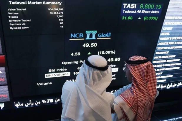 مستثمران يتابعان شاشة التداول في «السوق المالية» بالرياض (أ.ف.ب)