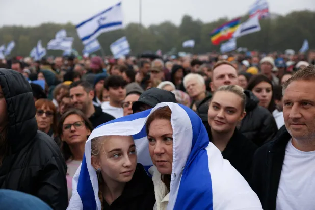 أشخاص يغطّون أنفسهم بعَلم إسرائيل خلال فعالية بلندن لإحياء ذكرى ضحايا هجوم 7 أكتوبر (رويترز)