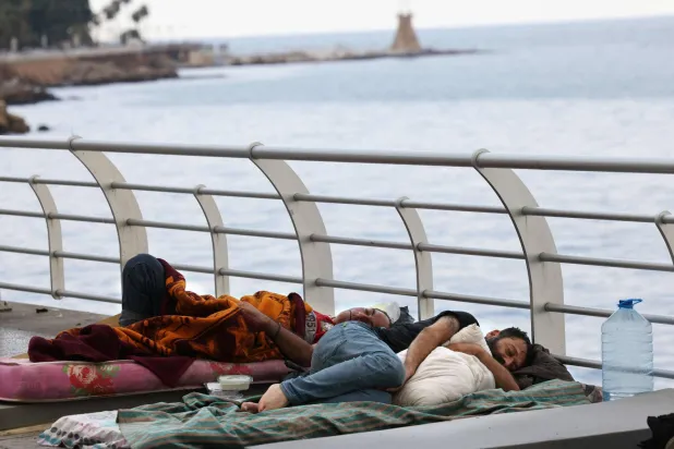 نازحون ينامون على رصيف الكورنيش البحري في عين المريسة في بيروت (أ.ف.ب)