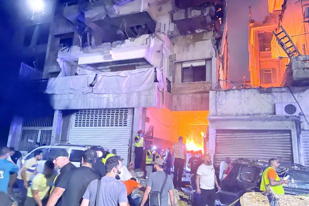 حشد من الناس أمام بناية استهدفتها غارة جوية إسرائيلية ليل أمس في محلة البسطا الفوقا قرب وسط بيروت (أ.ب)