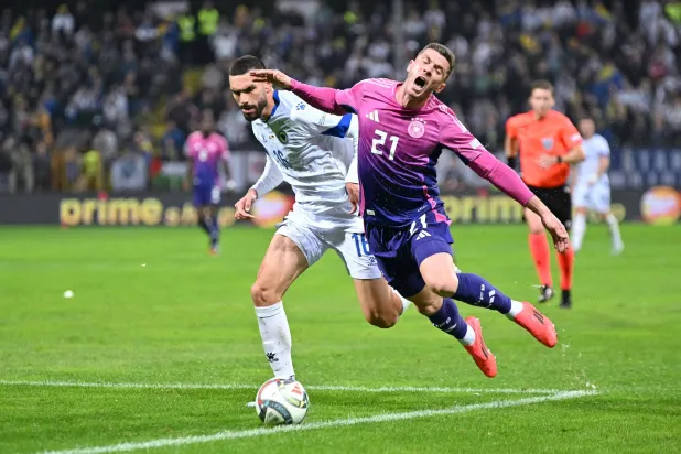 الألماني روبن جوسينس (يمين) يسقط أثناء صراعه على الكرة مع مدافع البوسنة  أدريان ليون (أ.ف.ب)