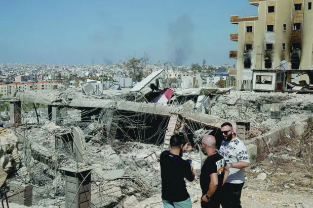 أشخاص قرب دمار سبّبه القصف الإسرائيلي في الضاحية الجنوبية لبيروت (رويترز)