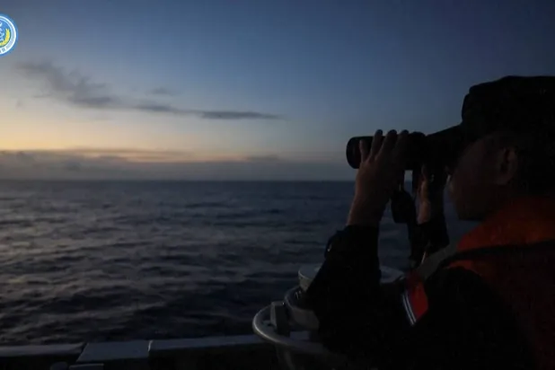 لقطة من فيديو للجيش الصيني تُظهر ضابطاً ينظر للأفق عبر منظار مكبر على متن قطعة بحرية (الجيش الصيني)