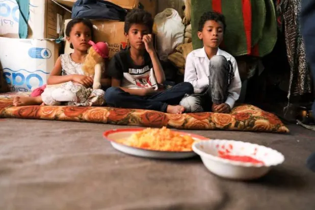 أطفال ينتظرون الغداء في كوخهم بصنعاء (رويترز)