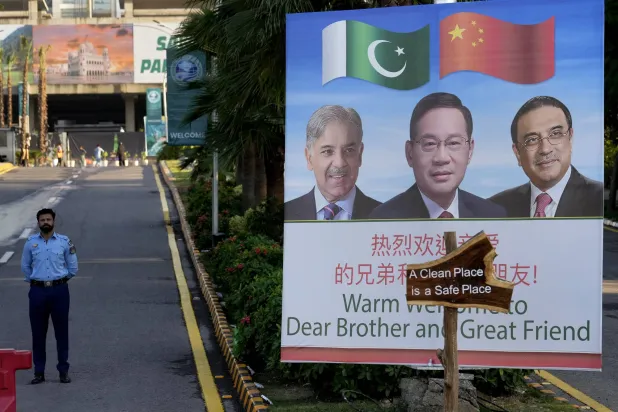 ضابط شرطة يقف حارساً بجوار لوحة إعلانية ترحيبية عليها صور رئيس الوزراء الصيني لي تشيانغ، في المنتصف، ورئيس الوزراء الباكستاني شهباز شريف، والرئيس آصف علي زرداري، على طول الطريق المؤدي إلى مكان انعقاد قمة منظمة شنغهاي للتعاون (أ.ب)