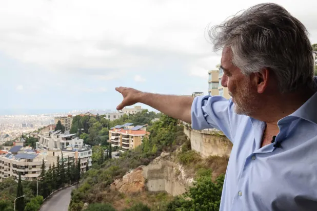الناطق باسم القوة المؤقتة للأمم المتحدة في لبنان (اليونيفيل) أندريا تيننتي يشير إلى الضاحية الجنوبية لبيروت من مكتبه في بعبدا قرب بيروت (أ.ف.ب)