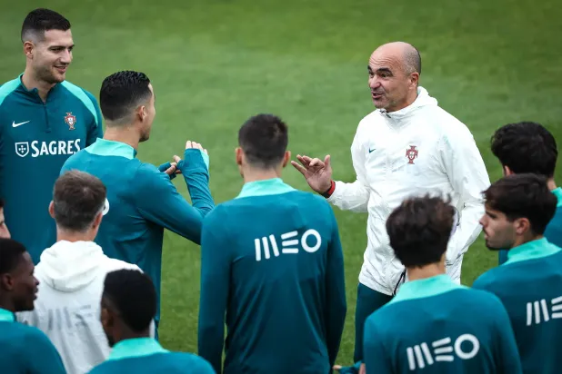 رونالدو يتحدث مع المدرب مارتينيز خلال تدريبات منتخب البرتغال بحضور اللاعبين (إ.ب.أ)