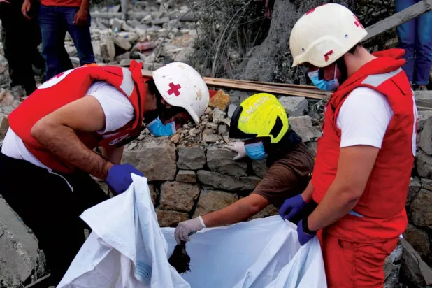 Kızıl Haç gönüllüleri, İsrail'in Lübnan'ın kuzeyindeki Aytu bölgesinde düzenlediği baskında ölen Lübnanlıların cenazelerini enkazdan çıkarırken (AP)