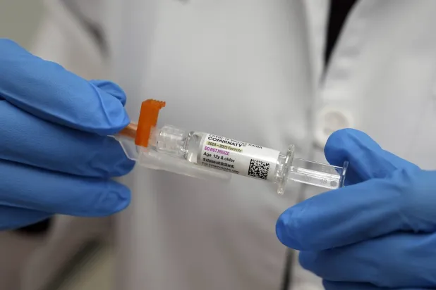 أحد العاملين في المجال الطبي يحمل جرعة من لقاح «كورونا» في نيويورك (أ.ب)