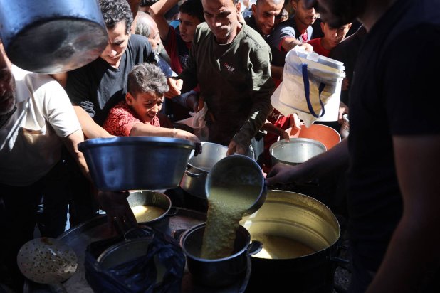 Displaced Palestinians queue to receive food rations, offered by a charity, in Gaza's Al-Shati refugee camp on October 17, 2024. (Photo by Omar AL-QATTAA / AFP)