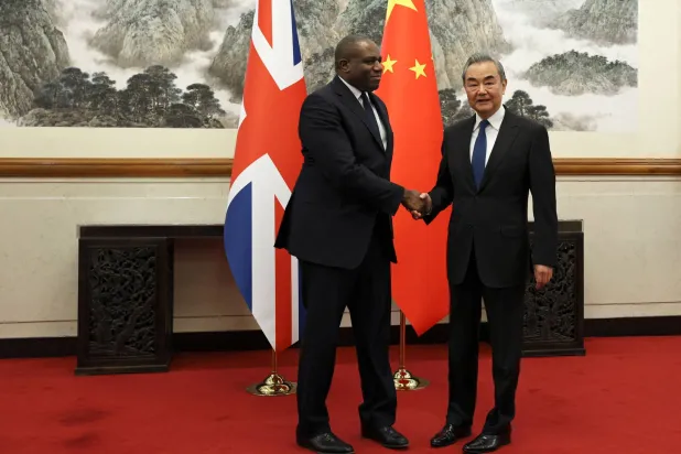 وزير الخارجية البريطاني ديفيد لامي مع نظيره الصيني وانغ يي (أ.ف.ب)