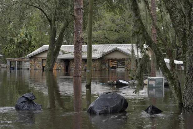 أكياس القمامة تطفو بالقرب من منزل غمرته المياه بسبب إعصار «ميلتون» على طول نهر ألافيا (أ.ب)