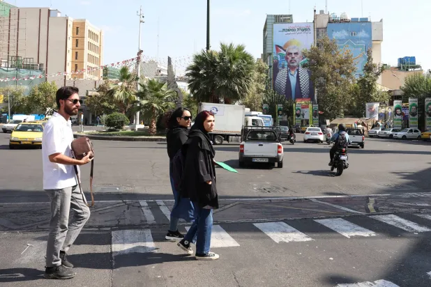إيرانيون يعبرون شارعاً أمام دعائية تحمل صورة يحيى السنوار في «ميدان فلسطين» وسط طهران (إ.ب.أ)