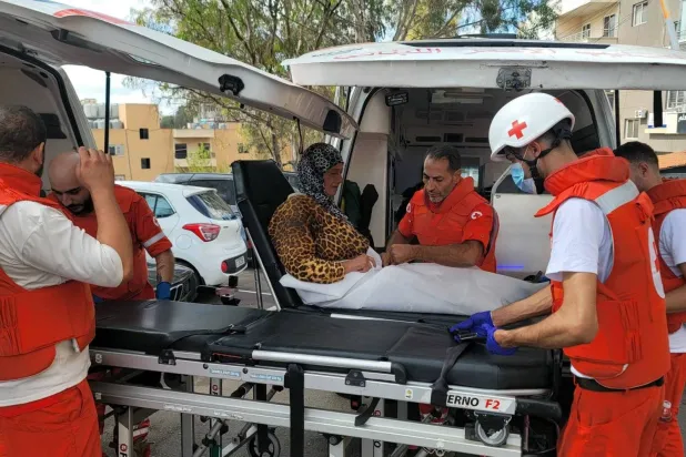 Volunteers from the Lebanese Red Cross rescue a woman in the city of Nabatieh in South Lebanon (AFP)