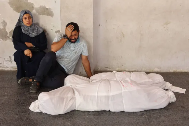 فلسطينيون أمام جثامين لذويهم الذي قتلوا في قصف إسرائيلي على شمال غزة أمس (أ.ف.ب)