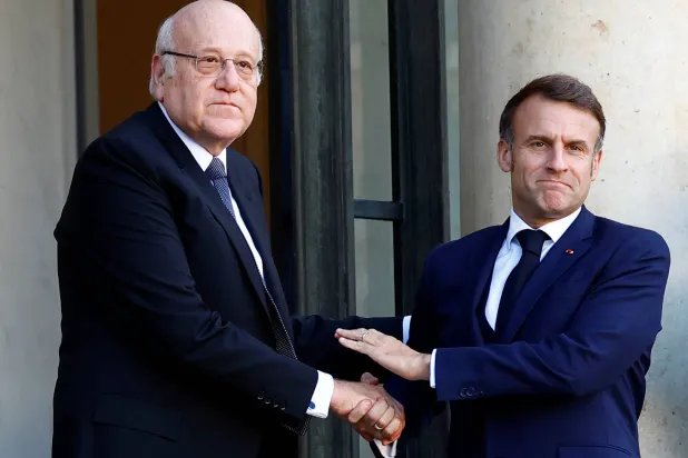 الرئيس الفرنسي إيمانويل ماكرون مستقبلاً على مدخل قصر الإليزيه نجيب ميقاتي عصر الأربعاء (رويترز)