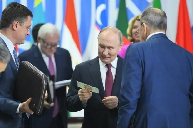 بوتين يعرض الورقة النقدية الرمزية التي تحاكي عملة المجموعة (نوفوستي)