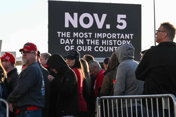 أنصار ترمب يحملون لافتة انتخابية تفيد بأن «5 نوفمبر هو أهم يوم في تاريخ بلدنا» بميشيغان 26 أكتوبر (أ.ف.ب)