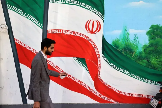 A man walks past a mural painting of Iranian flags in a street in Tehran on October 26, 2024. (AFP)
