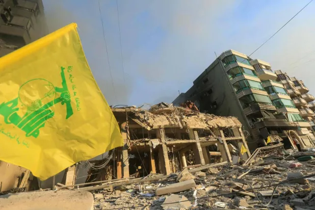 İsrail'in Beyrut'un güney banliyölerindeki binaları hedef aldığı yerin yakınlarında duran bir Hizbullah bayrağı (AFP)