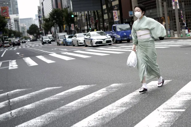 امرأة يابانية مرتدية الزي التقليدي «الكيمونو» تعبر طريقاً وسط العاصمة طوكيو (أ.ب)