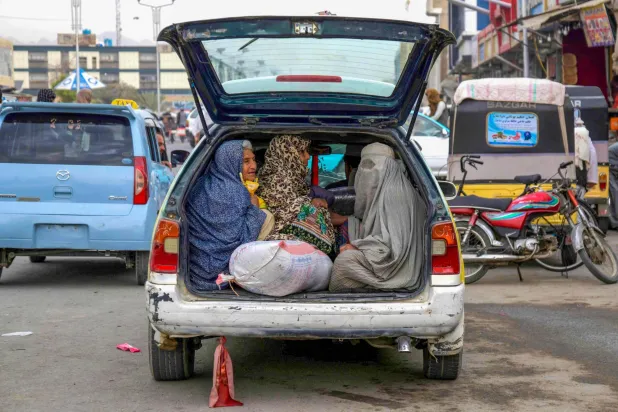 أفغانيات يجلسن في الجزء الخلفي من سيارة أجرة محلية على طول طريق في قندهار (أ.ف.ب)